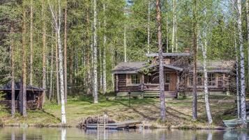 Une cabane avec un quai s’avançant dans un lac, entourée d’une forêt.