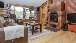 A cozy log cabin interior with a fireplace, a sofa, and a television.