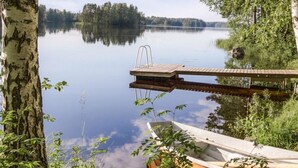 Un lago tranquilo con un muelle de madera y un bote pequeño.