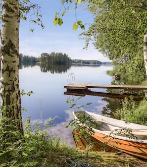 Un lago tranquilo con un muelle de madera y un bote pequeño.