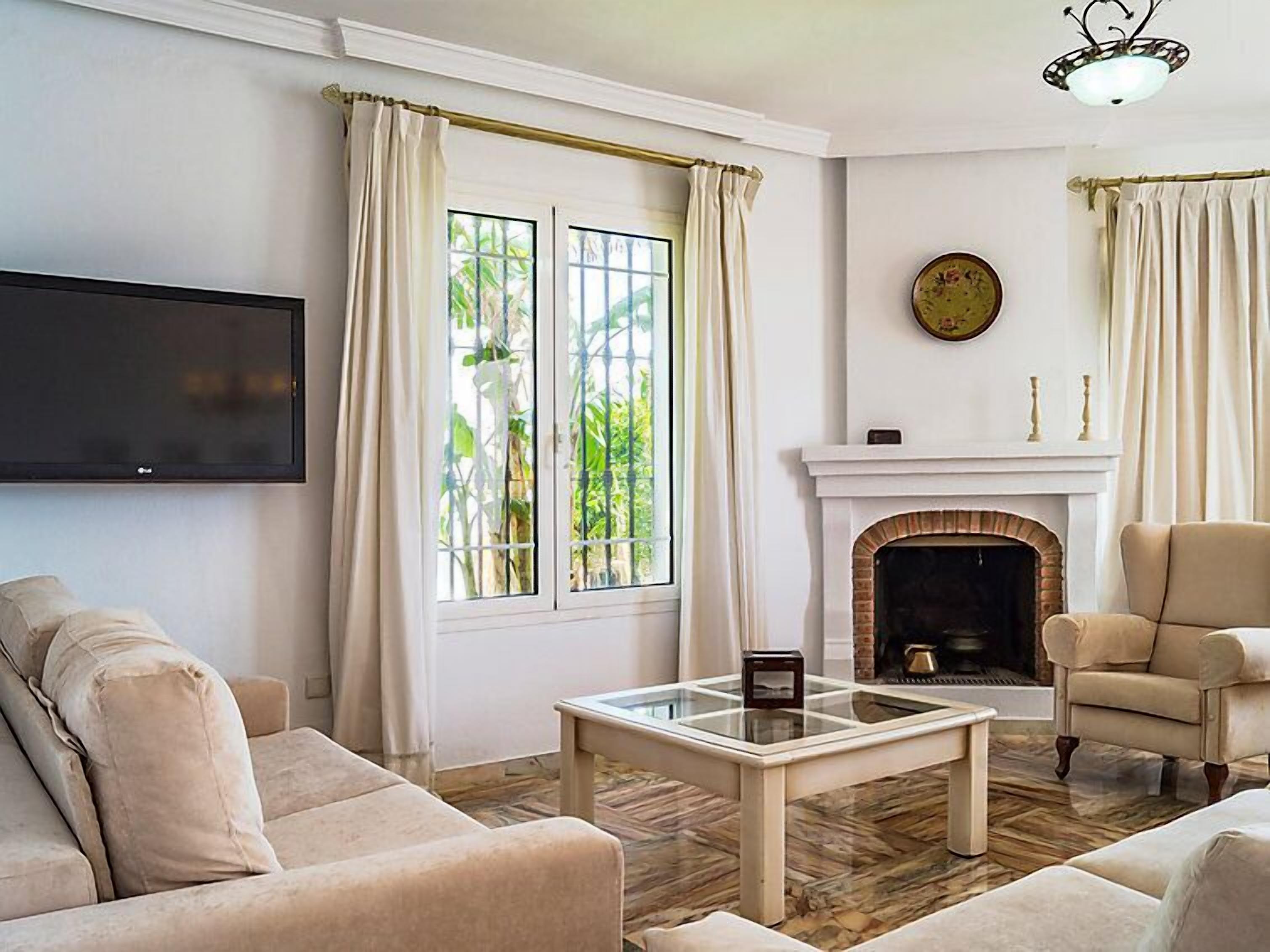 Una sala de estar con chimenea, televisor y sofá.