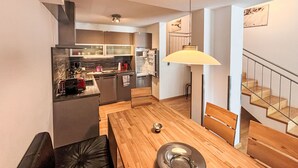 Une cuisine moderne avec un coin repas, des meubles en bois et un escalier.
