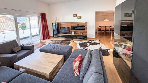 Un salon moderne comprenant un ensemble de canapés, une table basse, un téléviseur et un coin repas avec des chaises.