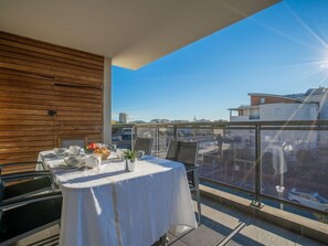 Un balcón con una mesa lista para comer, una pared de madera y una vista despejada del paisaje urbano.