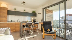 A modern kitchen with a dining area, a sofa, and a balcony with a view. - Rive Gauche by Interhome (Fréjus)