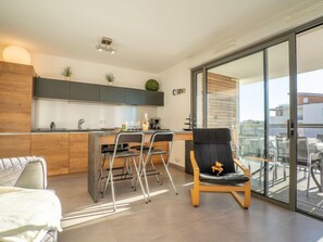 A modern kitchen with a dining area, a sofa, and a balcony with a view. - Rive Gauche by Interhome (Fréjus)