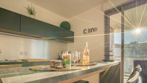 A modern kitchen with a bar area, a bottle of wine, and a view through a glass door. - Rive Gauche by Interhome (Fréjus)