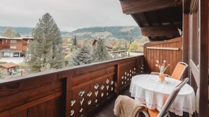 A wooden balcony with a table and chairs, overlooking a residential area with houses and trees. - Anna-Katharina by Interhome (Bad Hofgastein)