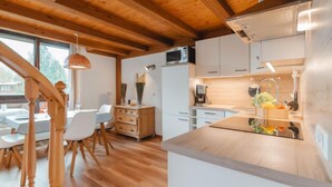 A modern kitchen with wooden beams, white cabinets, and a central island with a sink and fruit bowl. - Anna-Katharina by Interhome (Bad Hofgastein)