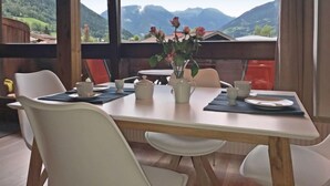 A dining area with a table set for two, a vase with flowers, and a view of mountains. - Anna-Katharina by Interhome (Bad Hofgastein)