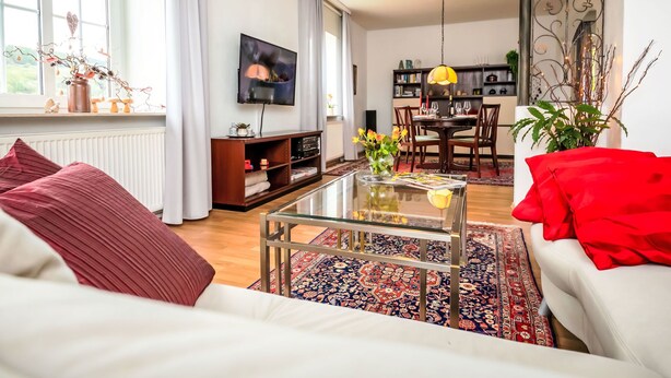 Un salon comprenant un canapé, une table basse et un téléviseur. Il y a également un coin repas avec une table et des chaises.