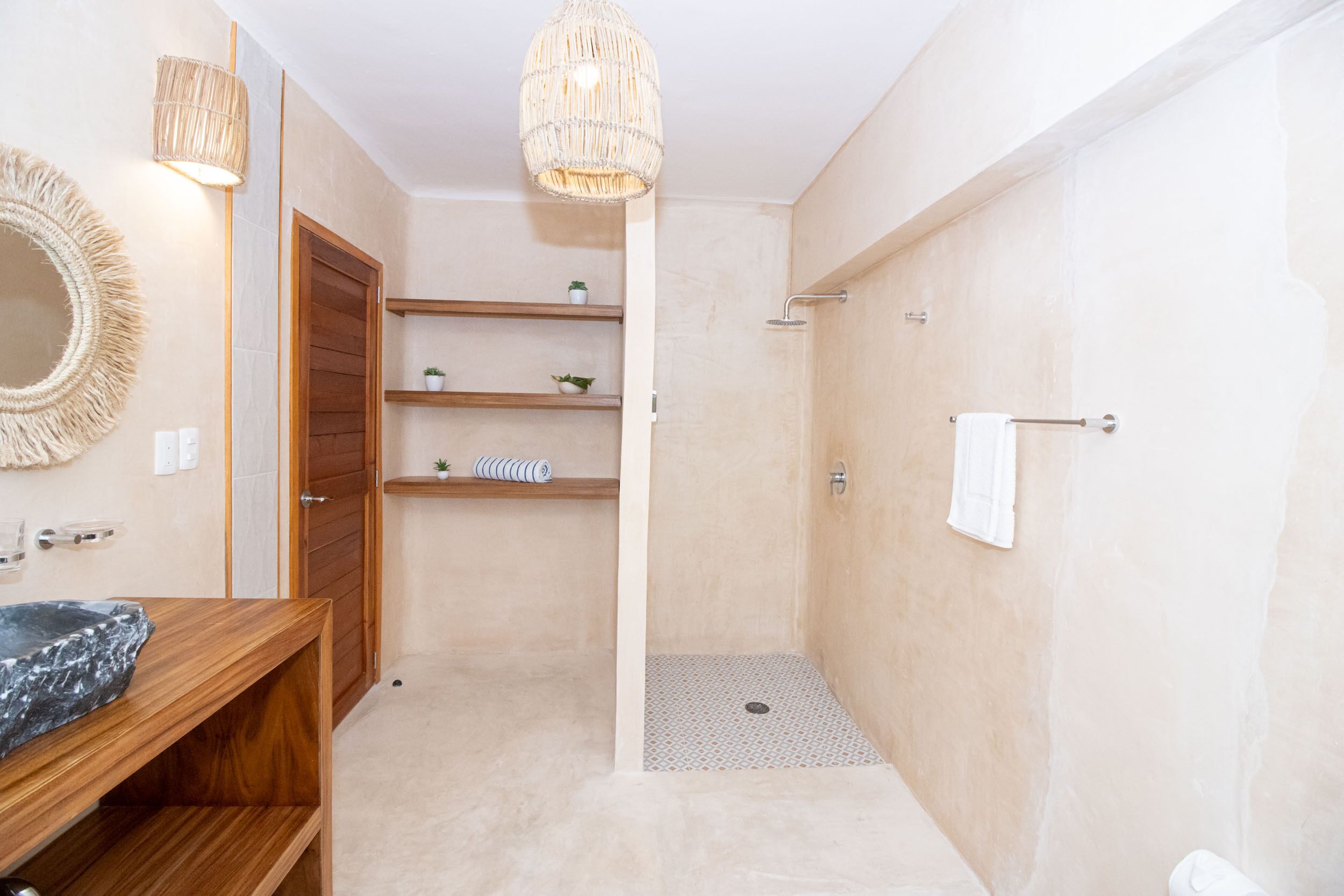 A modern bathroom with a wooden vanity, a large mirror, a shower with a glass door, and a hanging light fixture.