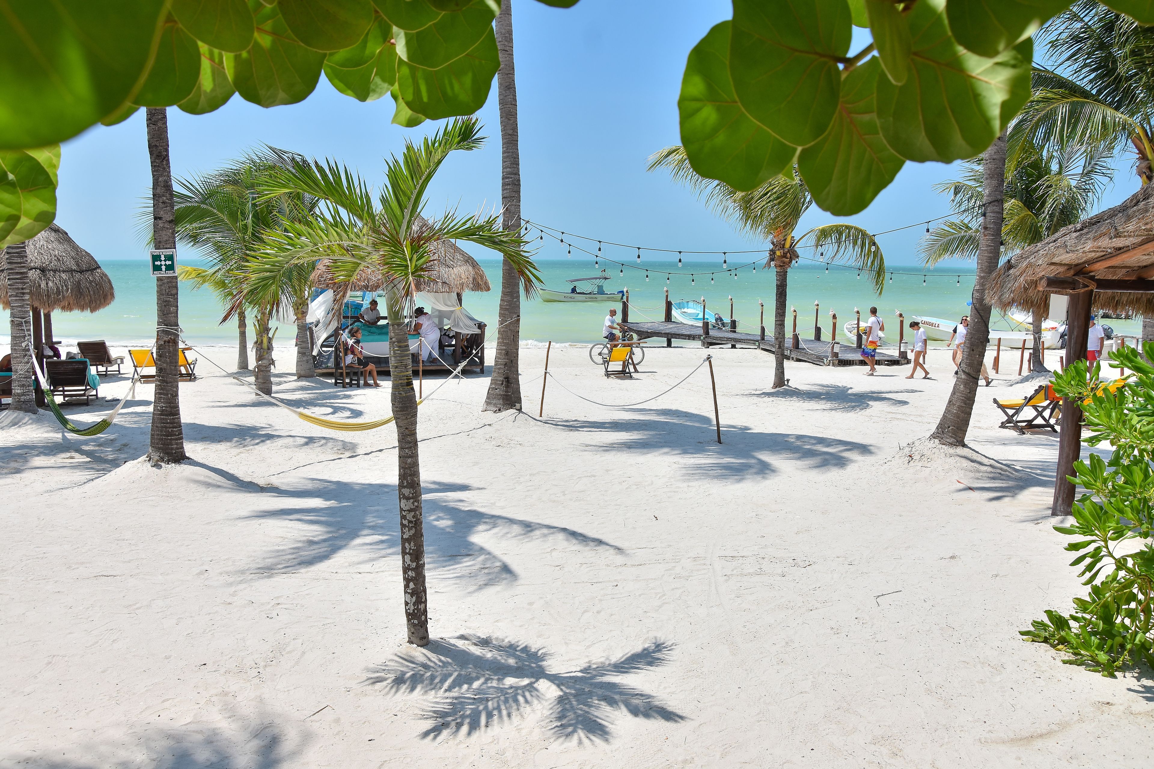 Une plage bordée de palmiers, avec des chaises de plage et une cabane à toit de chaume.