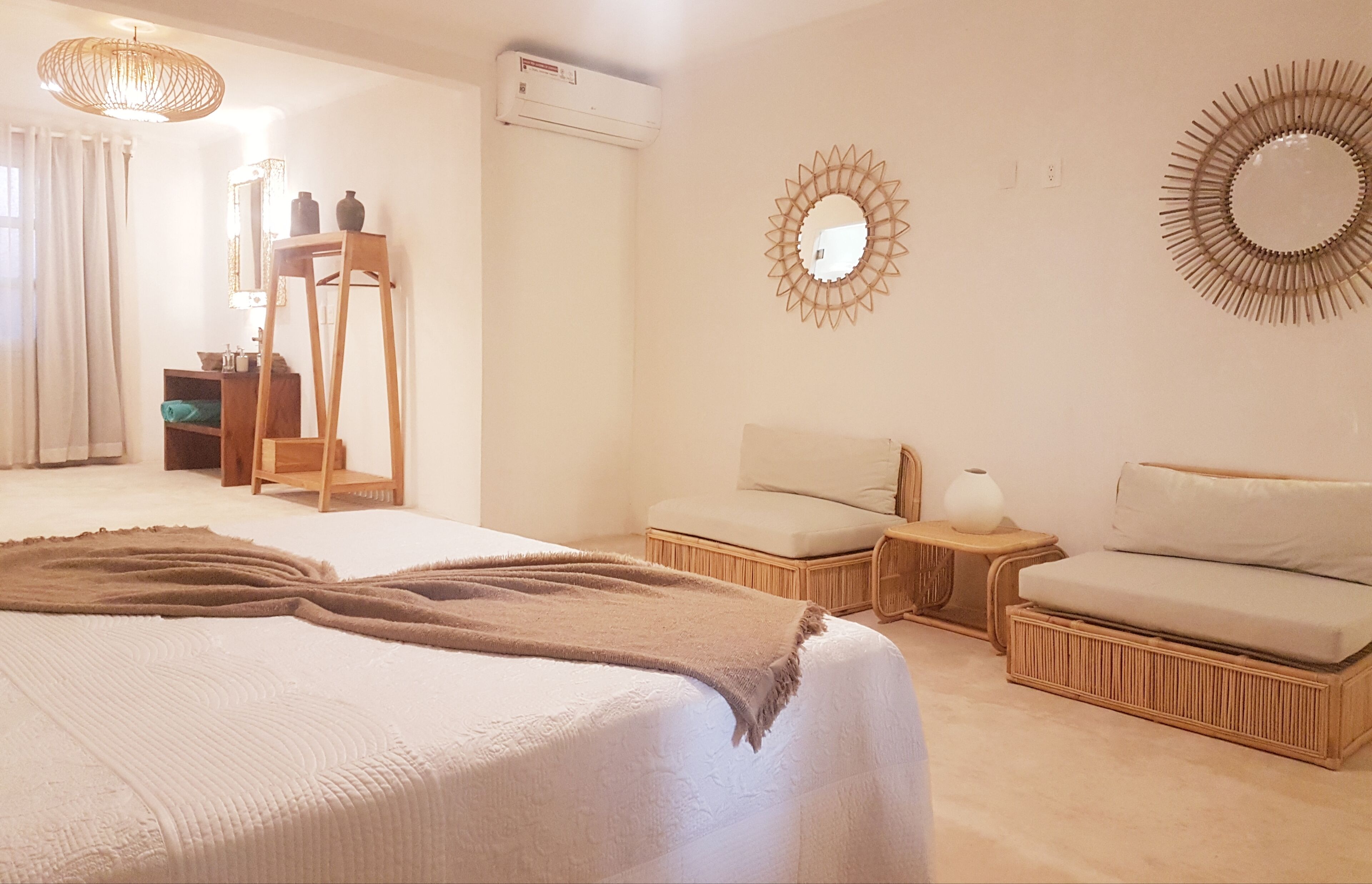 Un dormitorio con una cama grande, un sofá pequeño, una mesita de noche y un espejo en la pared.