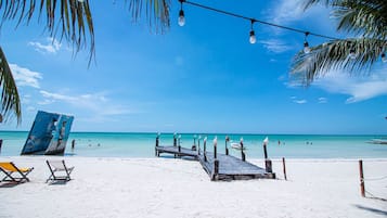 På stranden, vit sandstrand, solstolar och strandhanddukar