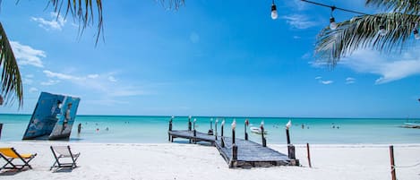 Na praia, areia branca, espreguiçadeiras, toalhas de praia 