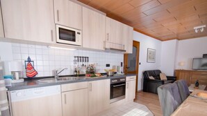 Una cocina moderna con armarios de madera clara, microondas integrado y una isla grande con pileta.