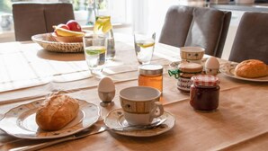 Un desayuno con platos de croissants, un jarro de miel, un frasco de mermelada y un vaso de agua.