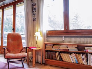 A cozy reading nook with a chair, a small table with a lamp, and a bookshelf filled with books.