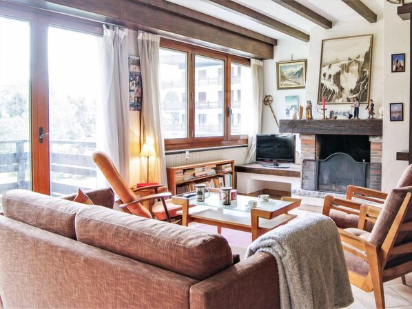 A cozy living room with a sofa, chairs, a coffee table, a fireplace, and a television.