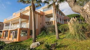 Un edificio de varios pisos con balcones, rodeado de palmeras y follaje.