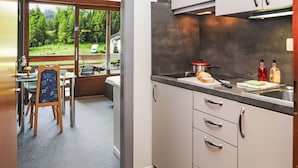 A modern kitchen with a view to a balcony, a dining area with a table and chairs, and a small refrigerator. - Rosablanche B22 by Interhome (Siviez-Nendaz)
