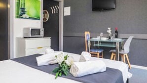 A hotel room with a bed, a desk with a computer, a TV on the wall, and a dining area with a table and chairs. - Rosablanche B22 by Interhome (Siviez-Nendaz)