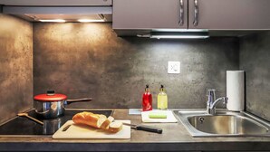 A kitchen with a stove, a cutting board with bread, a sink, and two bottles of soap. - Rosablanche B22 by Interhome (Siviez-Nendaz)