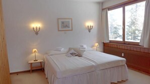 A hotel room with a double bed, two bedside lamps, a framed picture on the wall, and a window with curtains. - Chesa Cripels II by Interhome (St. Moritz)