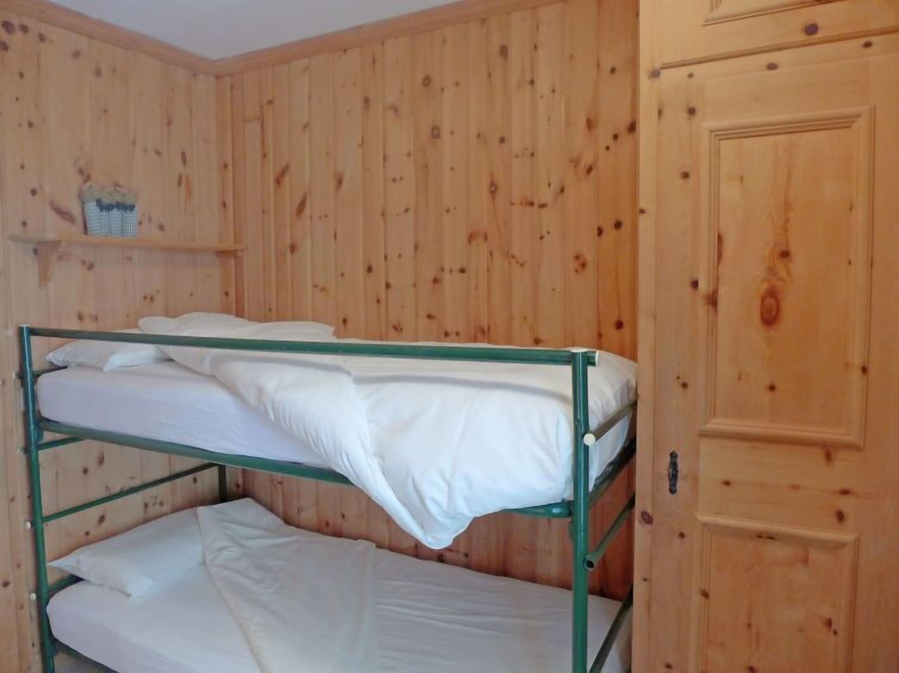 Une chambre avec un lit superposé, des murs en bois et une porte.
