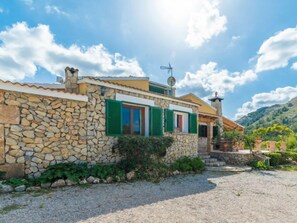 A stone house with green shutters, a satellite dish, and a mountain backdrop. - Villa Lavanda by Interhome (Alcúdia)