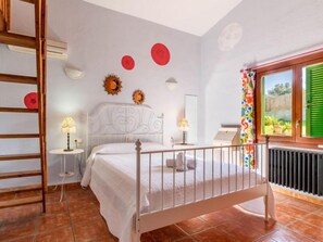 A bedroom with a bed, two bedside tables, a window with green shutters, and a radiator. - Villa Lavanda by Interhome (Alcúdia)