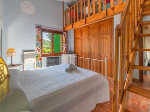 A bedroom with a bed, a wooden loft, a window with curtains, and a radiator. - Villa Lavanda by Interhome (Alcúdia)