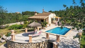 Une villa dotée d’une piscine, de murs en pierre et d’une toiture en chaume.