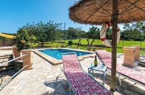 A poolside area with a thatched umbrella, lounge chairs, and a lifebuoy. - Villa Lavanda by Interhome (Alcúdia)