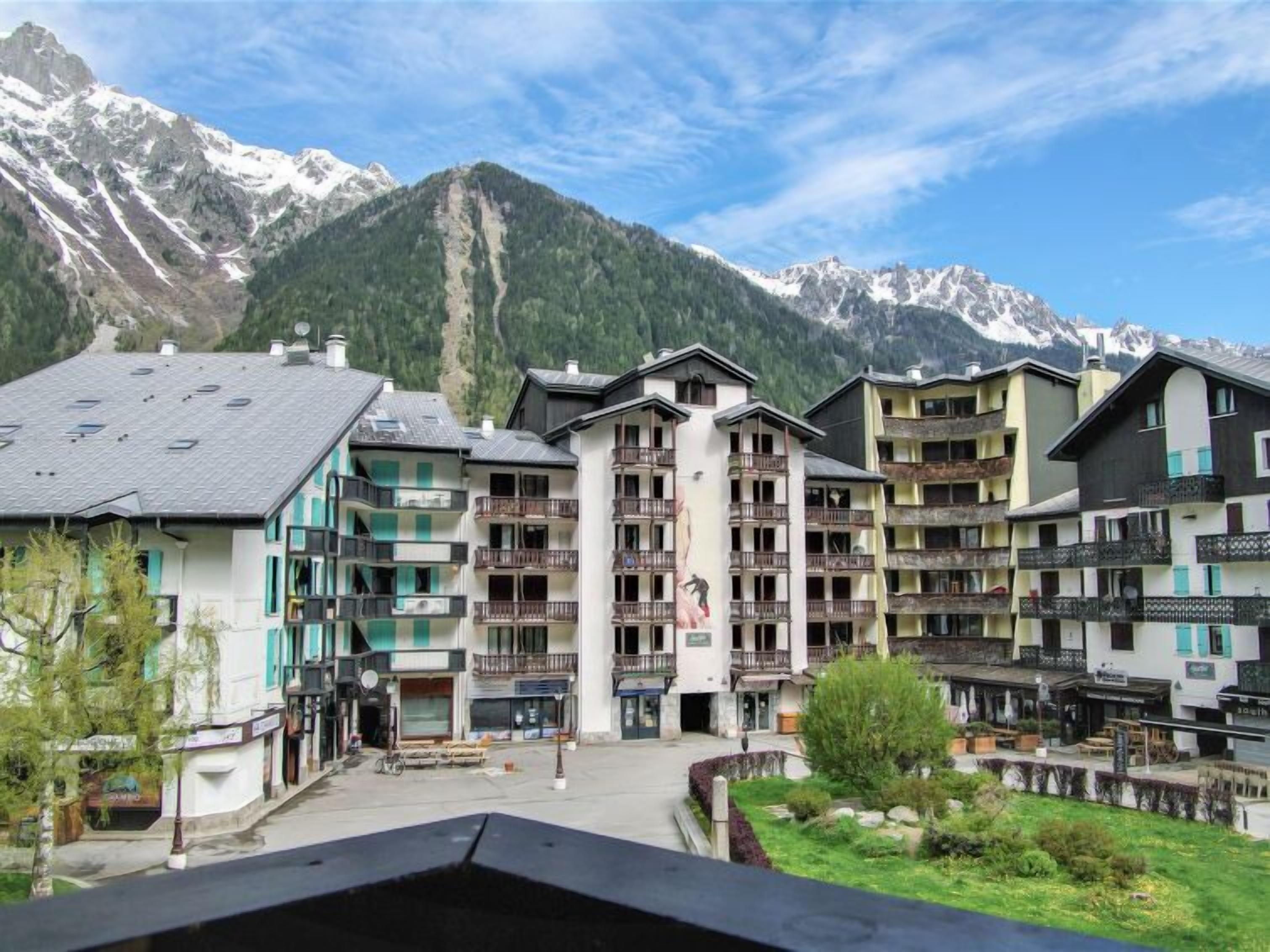 Une station de montagne avec des bâtiments à plusieurs étages, des balcons et une vue sur des sommets enneigés.