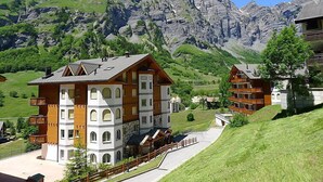 A chalet-style building with a sloped roof, multiple balconies, and a view of a mountainous landscape. - Edelweiss A by Interhome (Leukerbad)