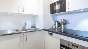 A modern kitchen with white cabinets, stainless steel appliances, and a black countertop.