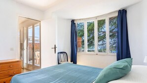 A bedroom with a bed, a chair, a dresser, and a window with curtains.