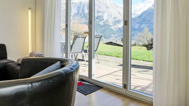 Une pièce dotée d’une grande porte-fenêtre coulissante donnant sur un patio avec vue sur les montagnes.
