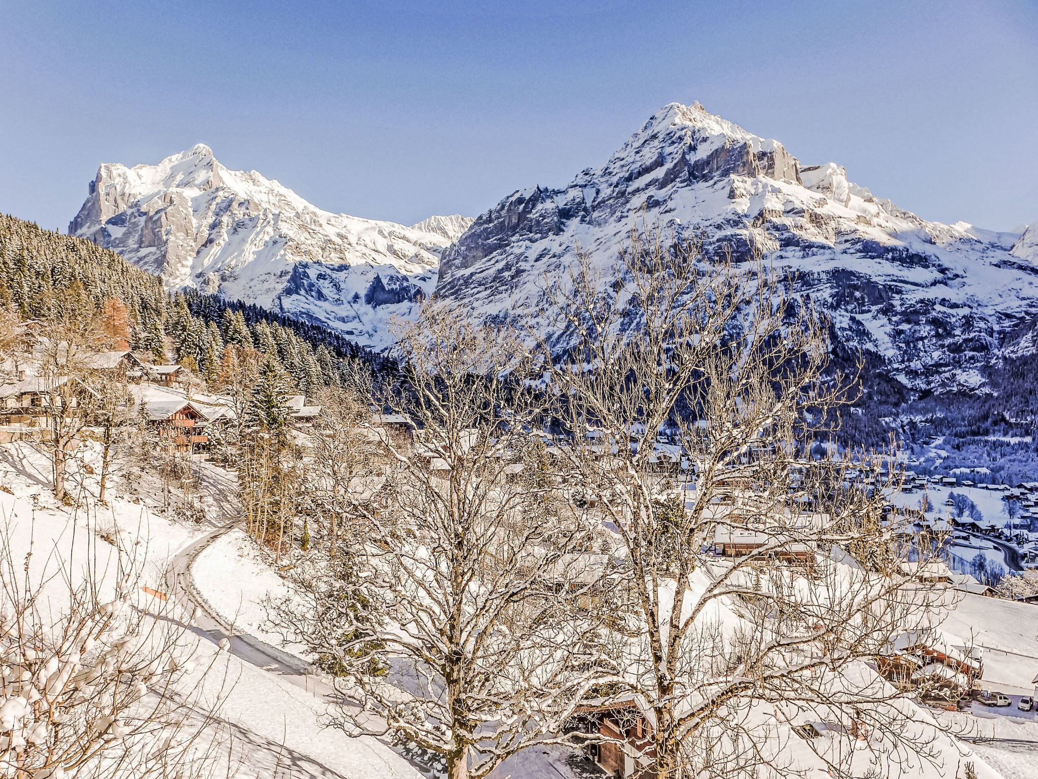 A mountainous landscape with snow-covered peaks and a ski trail.