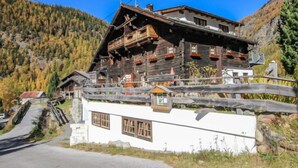 Ein traditionelles Holzchalet mit Balkon vor einer Bergkulisse.