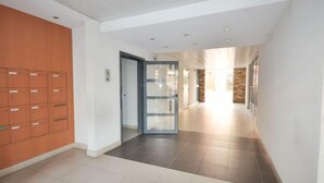 Un couloir avec des casiers sur le côté gauche, une porte en verre au centre et un mur de pierre sur le côté droit.