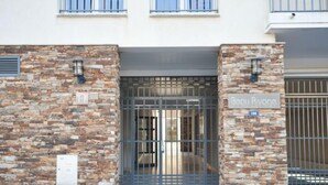 Une entrée d’immeuble avec une façade en pierre, un portail en métal et une enseigne indiquant « Beau Rivage ».