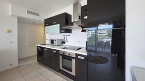 A modern kitchen with black cabinets, a stainless steel microwave, a stove, and a refrigerator. - Casta Diva by Interhome (Cannes)