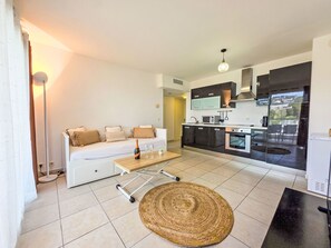 A modern living room with a sofa, a coffee table, and a kitchen area with appliances.