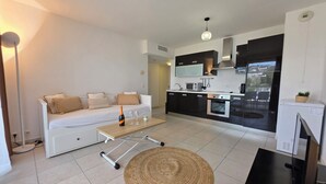 A modern apartment with a living area, kitchenette, and a dining table with a bottle and glasses. - Casta Diva by Interhome (Cannes)