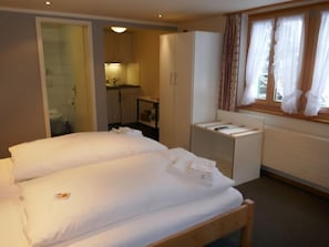 Una habitación de hotel con cama, kitchenette pequeña y baño.
