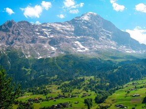 A mountainous landscape with a prominent peak, green valleys, and scattered houses.