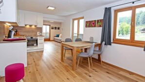 Una cocina moderna con armarios blancos, una mesa de comedor de madera y una vista luminosa por la ventana.
